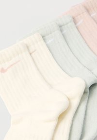 Négy pár pamut boka zokni krém, világos zöld, rózsaszín és szürke színekben. Minden pár bordázott textúrával és egy kis logóval a szegély közelében.