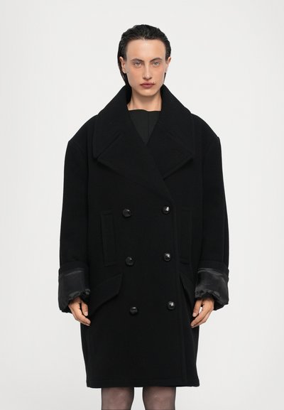 Sort uld peacoat med store revers, dobbeltstående knaplukning, sidelommer og satinforede manchetter. Minimalistisk design, mid-længde.