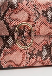 Borsa con motivo in pelle di serpente nei toni del rosa, marrone e nero, con una finitura testurizzata e un accento in metallo circolare dorato.