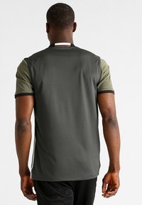 T-shirt med kort ärm i mörkgrön och olivgrön med en slät textur, kontrasterande krage och sidodetaljer i ränder.