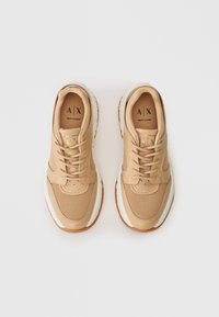 Beige Armani Exchange sportcipők fehér középtalppal és barna talppal, fűzve és felülről nézve, fehér háttér előtt.