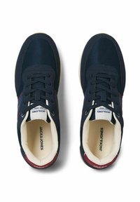 Baskets bleu marine avec dessus en mesh et tissu, lacets blancs, intérieur crème rembourré et accents rouges au talon. Semelle en caoutchouc robuste.