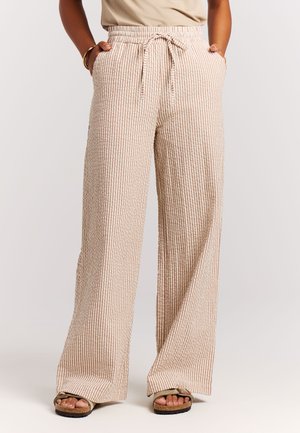 Lichtgewicht, wijde broekspijpen in een beige stof met subtiele bruine strepen. Voorzien van een elastische tailleband en zijzakken.