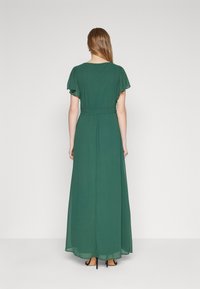 Rochie maxi verde cu mâneci scurte tip fluture, talie strânsă și material fluid. Prezintă o textură netedă, semi-transparentă și un design până la gleznă.