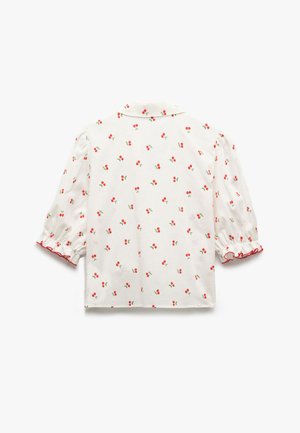 Valkoinen paita, jossa on punaisia kirsikkakuviot, lyhyet puffihihat ja punainen röyhelöhelma. Kevyt kangas, jossa on napillinen kaulus.