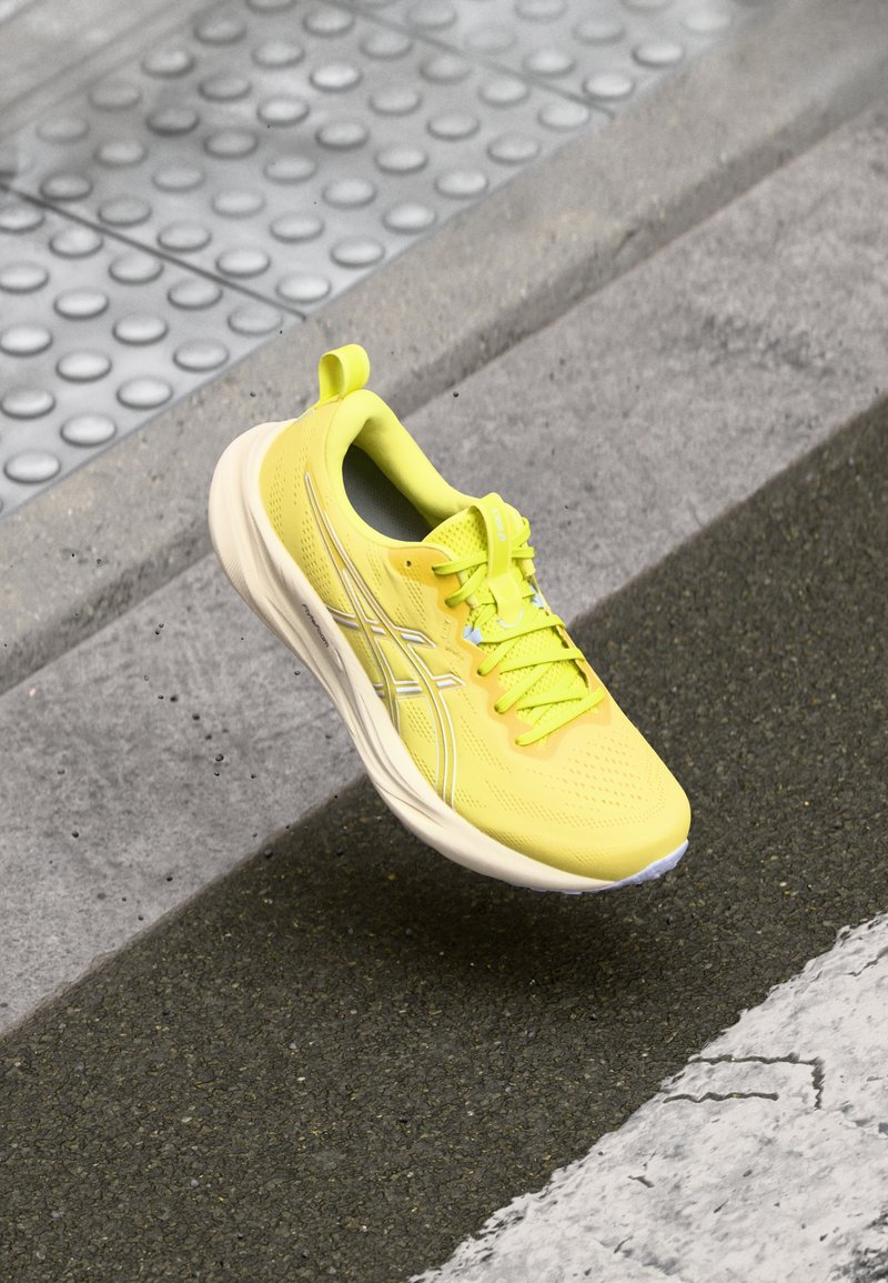 Yellow athletic shoe with a breathable mesh upper, synthetic accents, cushioned sole, and reflective detailing. Ideal for sports and running.