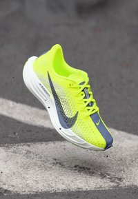 Nike running shoe features a neon yellow mesh upper with gray accents, a white midsole, and a textured sole for traction.