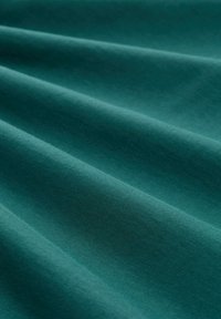 Tela verde azulado con una textura suave y mate, que presenta suaves pliegues y ondas. El material parece ligero y flexible.
