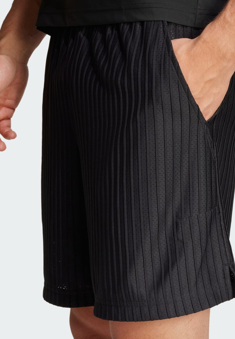 Pantaloni sportivi neri con strisce verticali testurizzate, vita elastica e tasche laterali per una maggiore funzionalità. Materiale leggero.