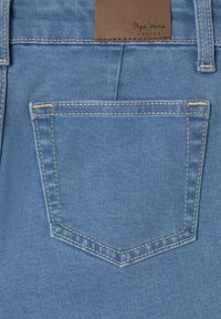 Plavi traper materijal sadrži stražnji džep s ušivenim rubom. Smeđa kožna oznaka na pojasu prikazuje "Pepe Jeans London."