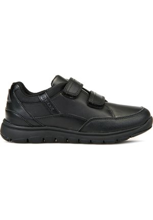 Zapatillas deportivas de cuero negro con punta redondeada, dos correas de Velcro y una suela de goma texturizada con patrones de agarre. Acentos de malla transpirable.