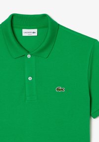 Green cotton polo shirt with a textured finish, featuring a two-button placket and a small embroidered logo in the chest area.