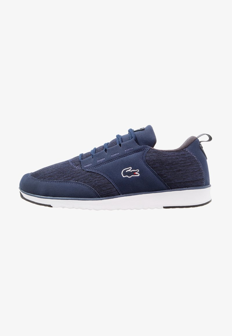 Baskets bleu marine avec dessus en mesh et daim, semelle blanche, design à lacets et petit logo crocodile sur le côté.