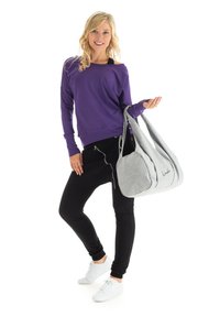 Purple long-sleeve sweatshirt, black fitted pants, and white sneakers. Gray oversized bag with two straps and embroidered logo detail.