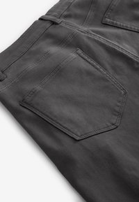 Donkergrijze broek met zichtbare achterzak en riemlus, met gedetailleerd stiksel en een gladde stoftextuur op een witte achtergrond.