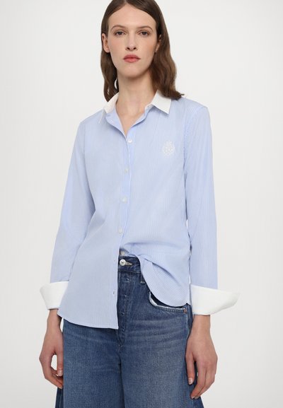 Light blue striped shirt with a white collar. Features long sleeves, front buttons, and a small embroidered logo on the chest.