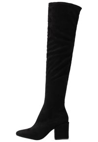 Stivale alto in suede nero con tacco a blocco e punta affusolata, esposto su uno sfondo bianco.