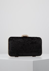 Černé sametové psaníčko se zlatým rámem a šperkovou sponou. Obdélníkový tvar, měkká textura a jemný lesk.