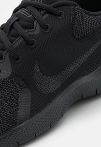 Černá sportovní bota s texturovanou síťovinou a hladkými panely, vybavená tmavým logem, šněrovacím designem a texturovanou gumovou podrážkou.