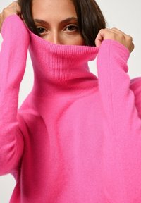 Maglione fucsia a collo alto realizzato in morbido tessuto a maglia, con colletto alto, maniche lunghe e vestibilità rilassata.