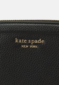 Black leather wallet featuring a textured finish, gold-tone logo "kate spade NEW YORK," and gold zipper detail along the top edge.