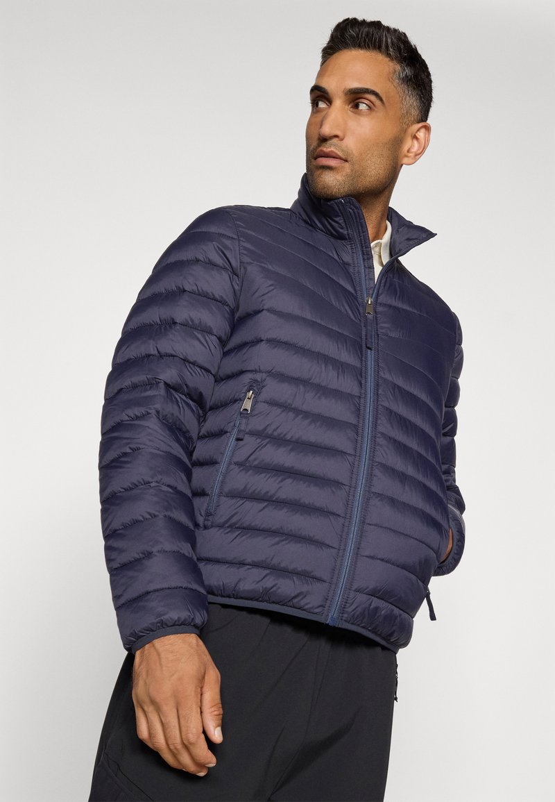Marineblaue Steppjacke mit horizontaler Steppung, hohem Kragen und Reißverschlusstaschen. Leichtes Material mit glatter Textur.
