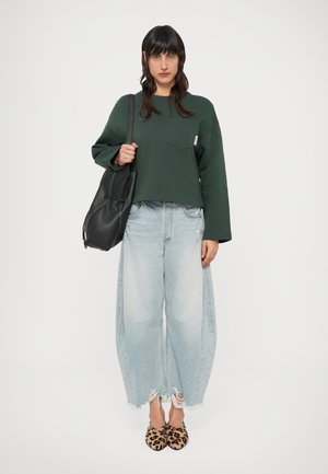 Sweatshirt verde curta com mangas compridas e bolso; jeans azul claro de perna larga com estilo desgastado; sapatos de bico fino com estampado de leopardo; mala preta.