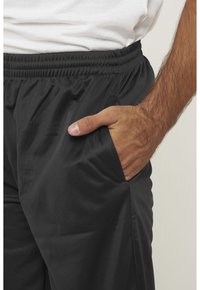 Zwarte sportlegging met een elastische tailleband, zijzakken en een soepele, gestructureerde stof.