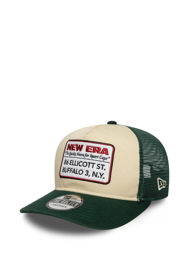 Zaļš un krēmīgs snapback cepure ar acu aizmuguri, kurai ir izcelta izšūta etiķete ar "NEW ERA" un atrašanās vietas detaļām.