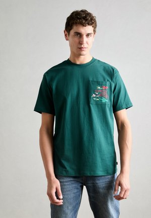 Zielony bawełniany t-shirt z krótkim rękawem, z kieszonką ozdobioną kolorowym haftem przedstawiającym ptaki i roślinność. Luźny krój.