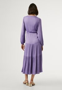 Robe longue violette à manches longues avec une taille froncée, une jupe à volants fluide et des manches volumineuses. Tissu doux avec une texture lisse.