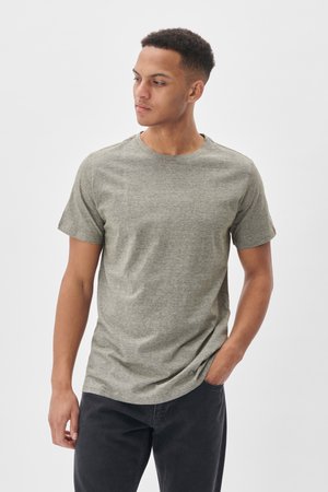 T-shirt gris mélange à manches courtes avec un col rond et une coupe décontractée, en tissu doux en mélange de coton. Porté avec un jeans foncé.