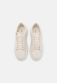 Baskets décontractées crème avec tige en cuir lisse, bout rond et fermeture à lacets. Présentent un logo discret sur la languette et une semelle intérieure rembourrée.