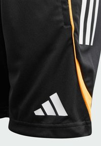 Crne atletske kratke hlače s bijelim Adidas logotipom i bijelim tri prugama, s narančastim bočnim panelom i detaljem džepa.