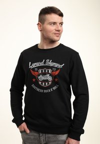 Černá mikina vyrobená z bavlny s dlouhými rukávy, se stylovým potiskem motocyklisty a textem "Lynyrd Skynyrd Southern Rock 'N' Roll."