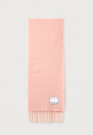 Écharpe en laine rose avec des franges aux extrémités. Présente une étiquette rectangulaire avec la marque "CPH STUDIOS". Texture douce.