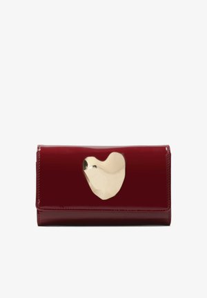Red patent leather wallet with a gold heart-shaped metal accent on the front. Compact rectangular shape, smooth texture, and clean finish.
