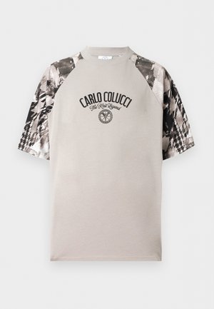 T-shirt beige à manches courtes avec manches à motif abstrait noir et blanc et texte et logo "CARLO COLUCCI The Knit Legend" sur la poitrine.