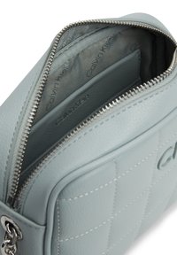 Borsa in pelle trapuntata azzurro chiaro di Calvin Klein con zip argentata e texture liscia. L'interno presenta scomparti multipli e fodera con stampa del logo.