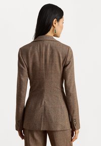 Ruskea teksturoitu bleiseri, jossa on räätälöity istuvuus, huippulapelit ja hienovarainen ruutukuosi; se sisältää kolme nappia jokaisessa hihassa ja takakäynti.