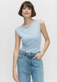 Ljusblå ärmlös topp med draperad design, mjukt tyg och båtformad halsringning. Matchas med högmidjade ljusa denimjeans.