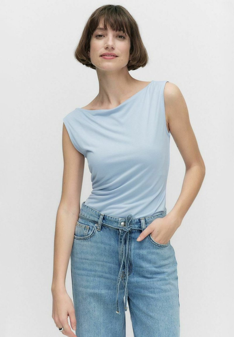 Ljusblå ärmlös topp med draperad design, mjukt tyg och båtformad halsringning. Matchas med högmidjade ljusa denimjeans.