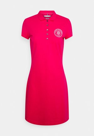 Lys pink polo-kjole med korte ærmer, fem knapper og en cirkulær Tommy Hilfiger-logo på venstre bryst.