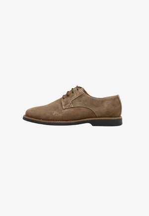 Zapato Oxford de hombre de ante marrón con cordones, suela negra y costuras beige, mostrado de perfil sobre fondo blanco.