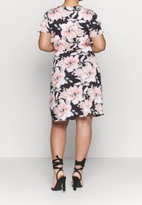 Kwiecista sukienka z krótkimi rękawami, czarna baza, duży wzór różowych i niebieskich kwiatów oraz dopasowana talia. Połączona z czarnymi szpilkami z paskami.