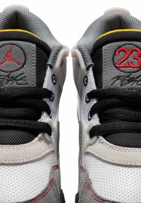 Szare i czarne sneakersy z białą perforowaną skórą, czerwonymi akcentami, siateczkowym wykończeniem oraz charakterystycznym logo na języku, z misternym przeszyciem.