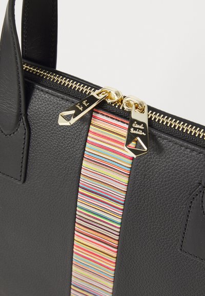 Bolsa de mão em couro preto com superfície texturizada, zíperes dourados e um detalhe central em tecido listrado multicolorido com acentos do logotipo.