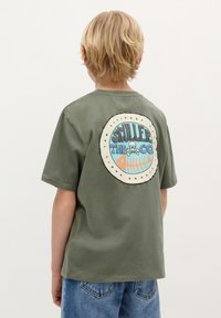 Groene katoenen T-shirt met een ronde graphic op de achterkant met een doodskop en vis ontwerp in blauw en oranje. Ronde hals en korte mouwen.