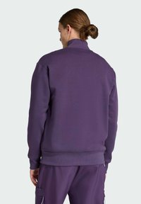 Felpa viola con collo alto, polsini e orlo a costine, realizzata in un materiale morbido, caratterizzata da un design minimalista.