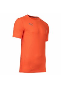 Pomarańczowa koszulka sportowa z krótkim rękawem, wykonana z teksturowanej tkaniny, z małym szarym logo Puma na piersi i okrągłym dekoltem.